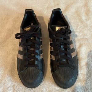 “Superstar” by ADIDAS. Black w/copper/tan stripes, 9 1/2. Brand new/Never worn.